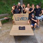 équipe d'apprentis posant devant leur radeau en carton